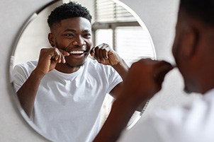 Man smiling while flossing his teeth