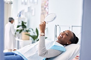 Woman smiling at reflection in handheld mirror