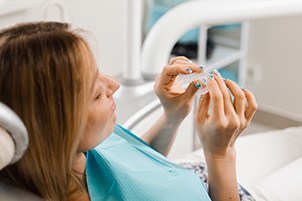 Patient holding clear aligner in treatment chair