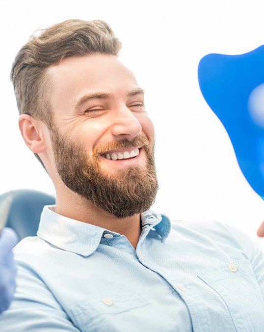 patient smiling while looking in dental mirror