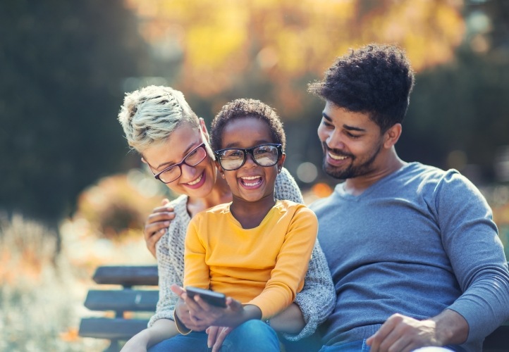 Family of three sitting on park bench after contacting Saint Peters dental office