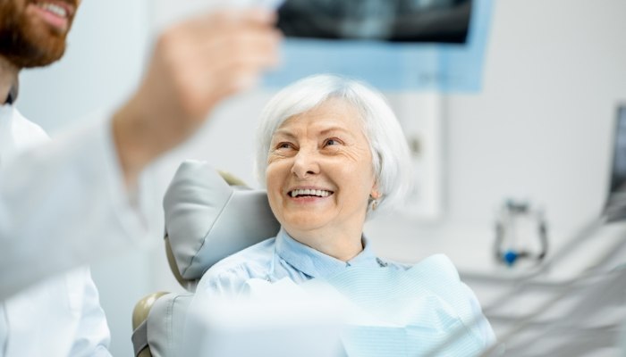 Senior woman smiling at her dentist during dental implant consultation