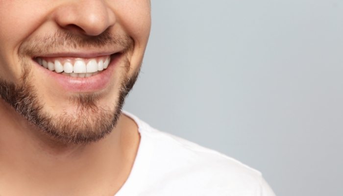 Close up of a man in a white tee shirt smiling