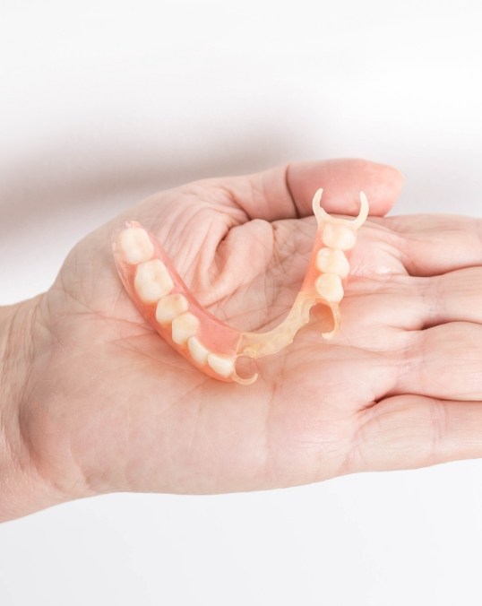 Person holding a partial denture in their hand