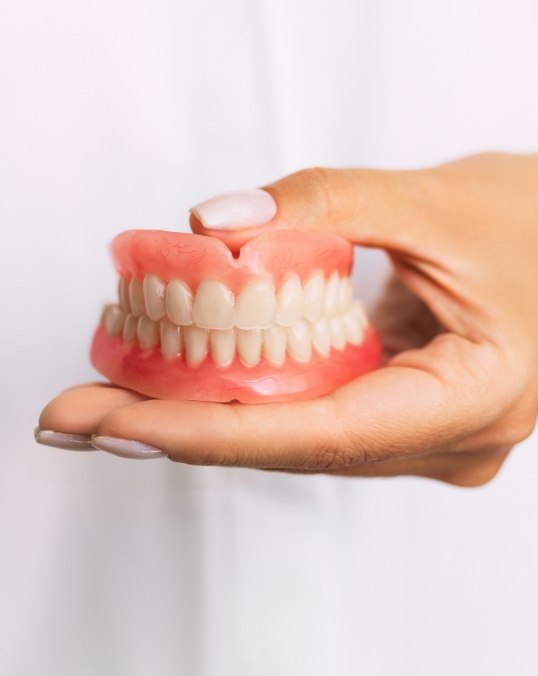 Dentist holding a set of full dentures in their hand