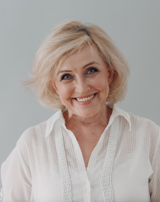 Senior woman in white collared shirt grinning