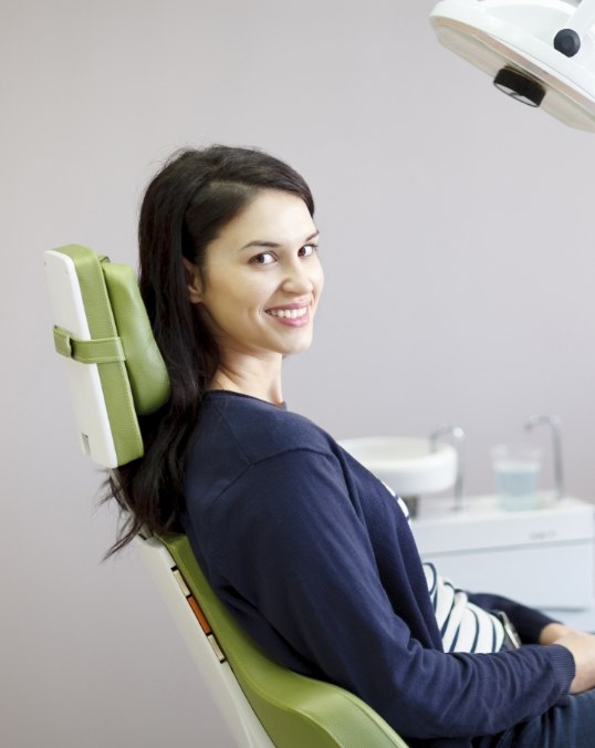 Woman in navy blue blouse smiling in dental chair