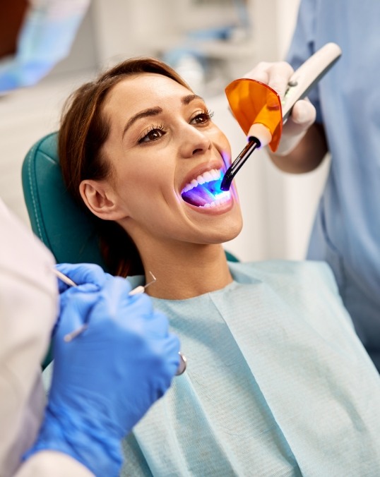 Cosmetic dentist performing direct bonding on a female dental patient