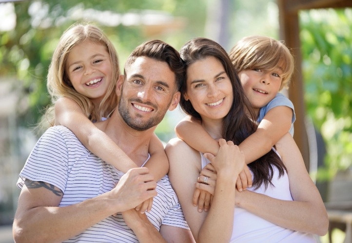 Mother father and two children smiling outdoors after visiting their family dentist in Saint Peters