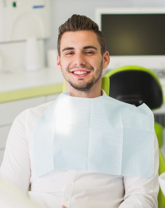 Man in white button up shirt smiling during dental checkup