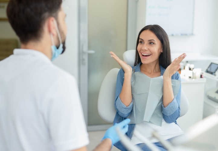 Woman in dental chair beaming at her dentist
