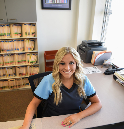 Smiling dental team member sitting at front desk