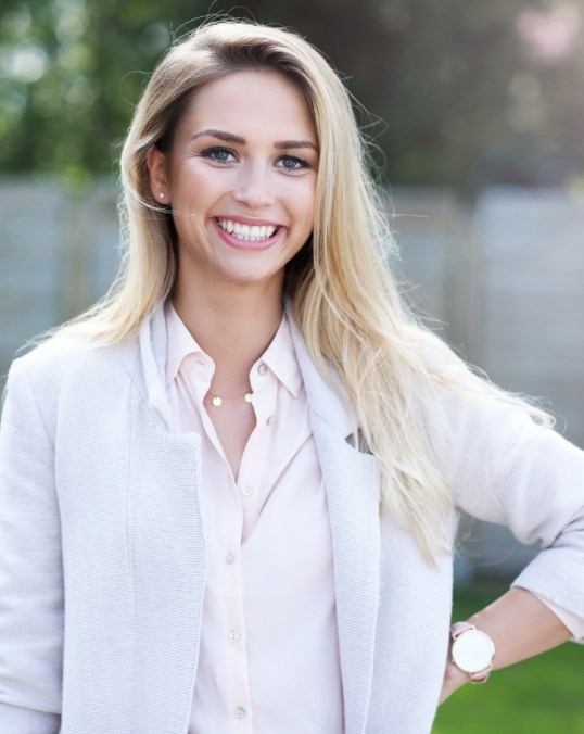 Woman in white business attire smiling outdoors