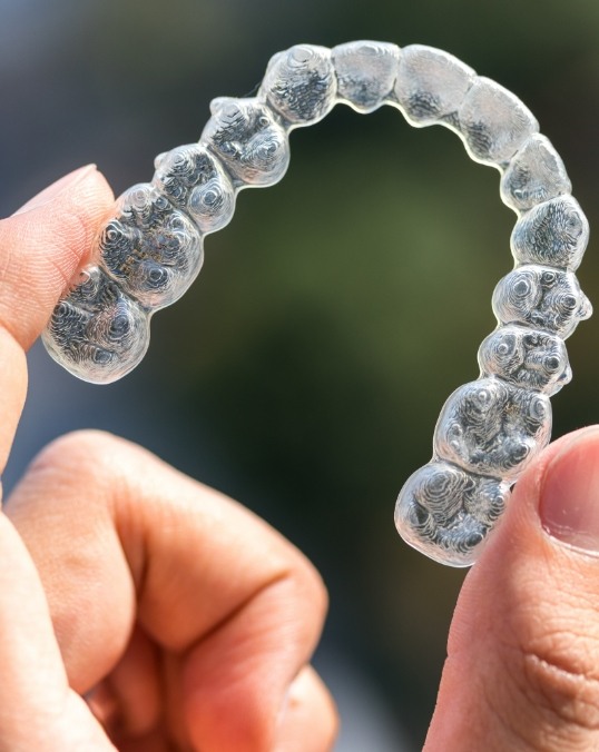 Invisalign aligner being held in a person's hand