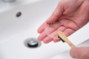 Patient using toothbrush to clean their aligners