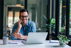 Man smiling while talking on phone in home office