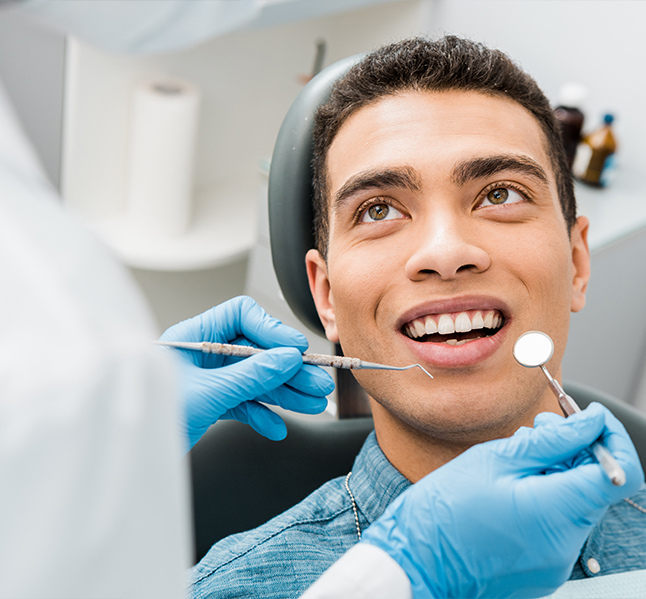 Man in denim shirt smiling at his dentist during dental checkup