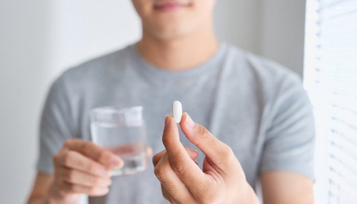 a person with dental implants taking an over-the-counter painkiller