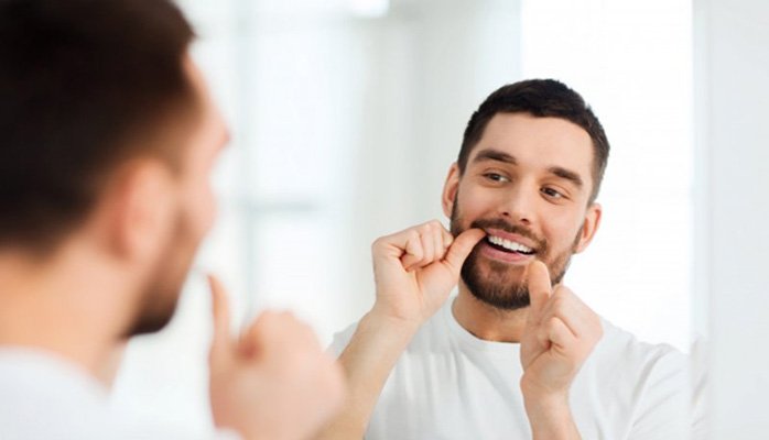 a man flossing his dental implants in Saint Peters