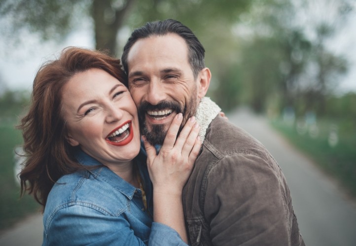 Man and woman hugging and laughing outdoors after preventive dentistry in Saint Peters