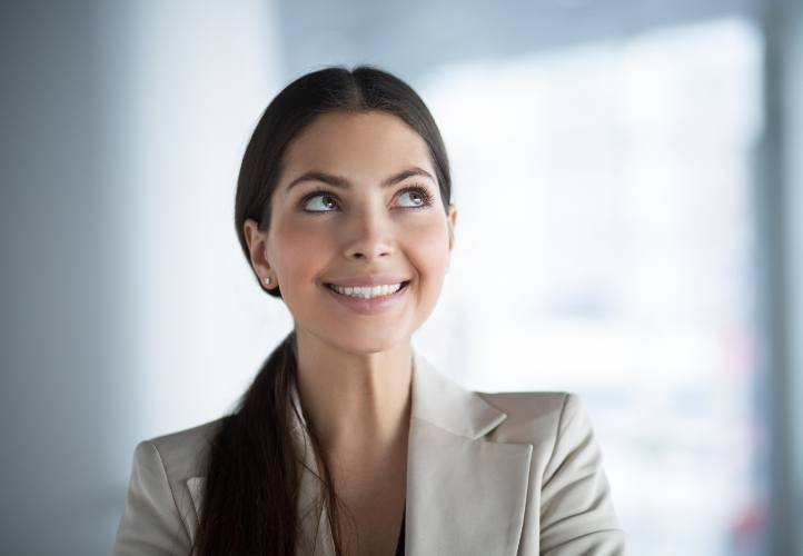 Woman in beige business jacket smiling after root canal treatment in Saint Peters