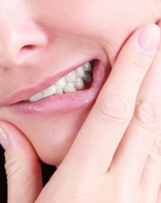 Close up of a person holding their cheek in pain