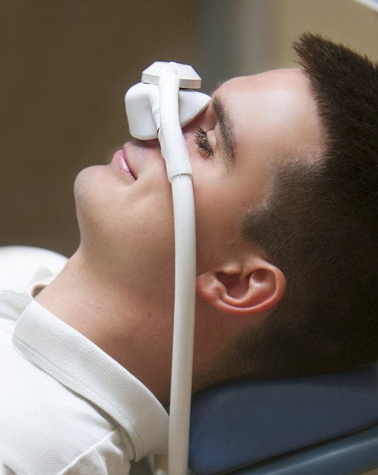 Man laying in dental chair with nitrous oxide sedation mask over his nose