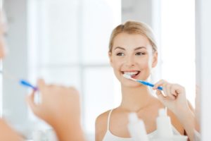 Woman looking in mirror while brushing her teeth