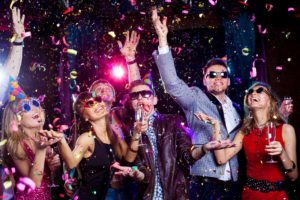 Group of people with sunglasses and champagne partying in falling confetti