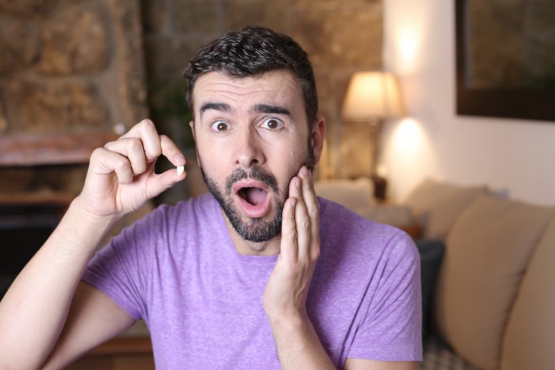 A young man holding a lost tooth